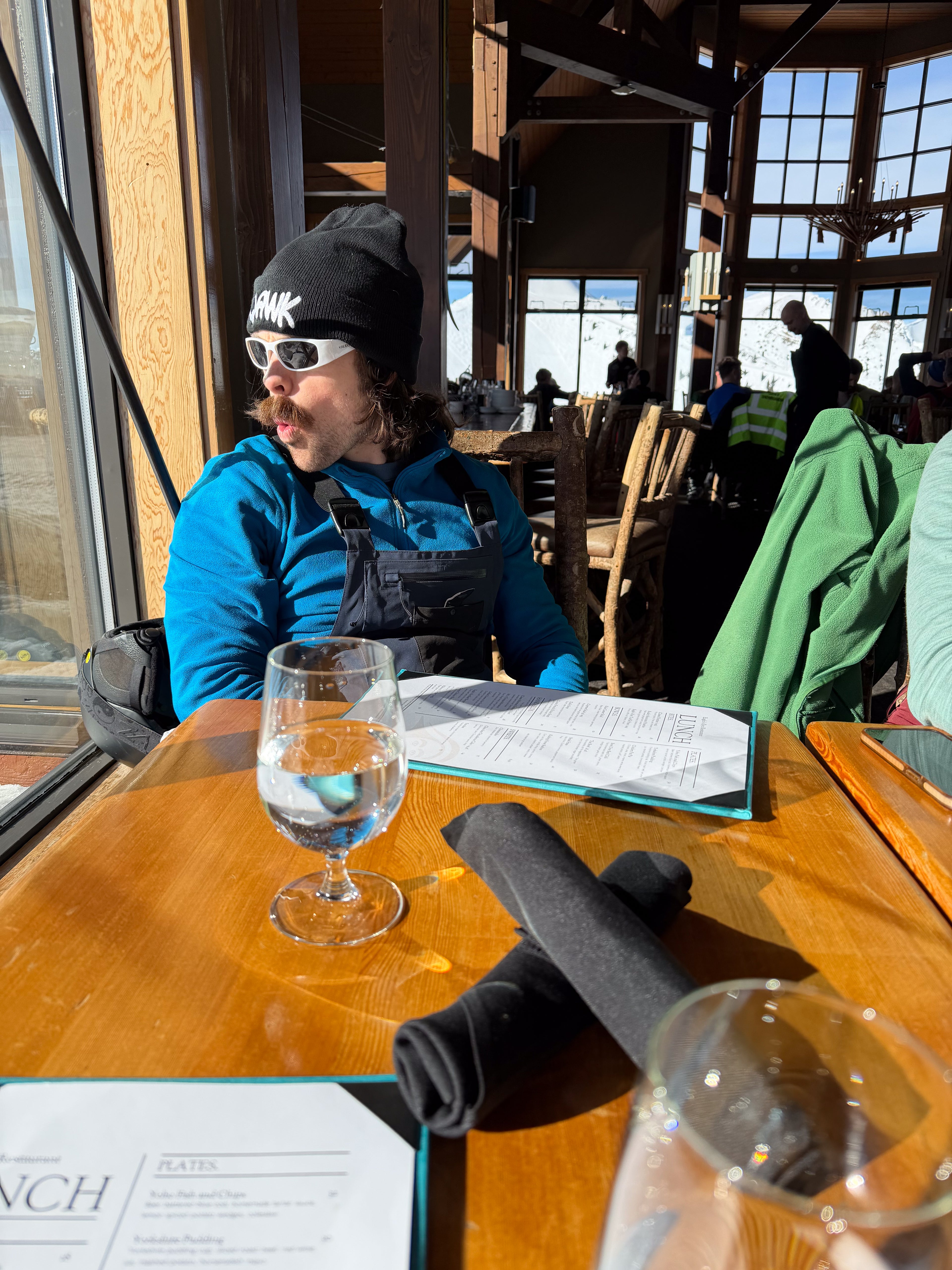 Man wearing SQAWK Beanie and sunglasses looking out window excitedly.